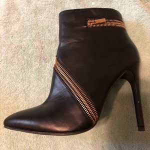 Black ankle high boots with gold zippers.